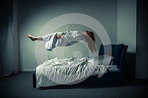 Girl in nightgown sleeping and levitating