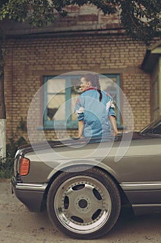 Girl in the nineties sitting on hood of car