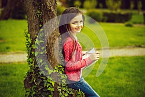 Girl with notebook and pen near tree