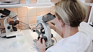 The girl nurse carefully examines the bacteria through a microscope