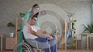 Girl nurse helps in the rehabilitation of a disabled person in a wheelchair