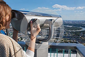 Girl on the observation deck , moscow city panorama. Woman looks binoculars at the city on the observation deck