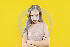 The girl is offended. Displeased teenager on a yellow background. Disappointment