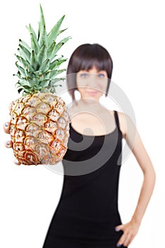 Girl offering a pineapple (focus on foreground)