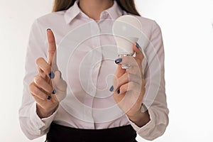 Girl in office clothes holds a light bulb in hand