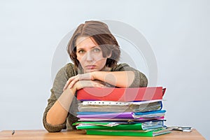 Girl office staff thoughtfully leaning on a stack of folders