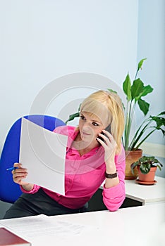 Girl in the office talking on the phone and looking at papers