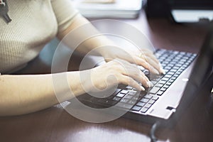 Girl in the office is typing on a laptop. girl at work. girl hands on keyboard