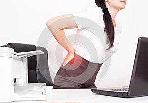 Girl office worker holding her aching back from a chair, the concept of back pain in office workers, lactic acid in muscles and photo
