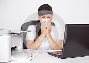 Girl office worker sits at a computer in the office and blows her nose the concept of allergies to dry and humid air as well as