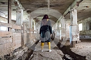 A girl in an old abandoned scary room like a barn or stable. An abandoned factory barn and stable where cows and horses lived.