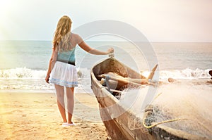 Girl at the old fishing boat looking to the ocean