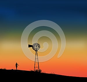 A girl and an old windmill are seen silhouetted at sunset.