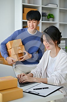 A girl is an online business owner, confirming order on the website while working with her boyfriend photo