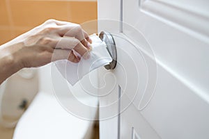 Girl open the door of a public toilet,hand of woman using tissue paper to touch the door knob instead of hands to prevent