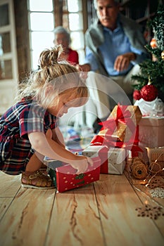 Girl open present in front of a decorated Christmas tree