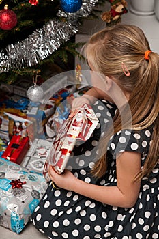 Girl opening Christmas present under Christmas tree