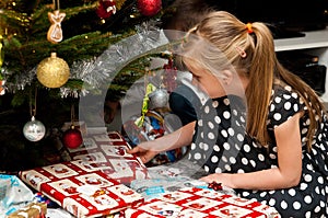 Girl opening Christmas present under Christmas tree
