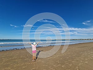Girl opening her arms in front of the sea with a seagull flying in front of her. photo