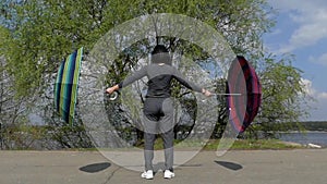 Girl in Opening Umbrellas in Slow Motion. She Standing in Sport Suit.