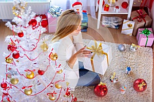 Girl opens New Year`s gift at the Christmas tree