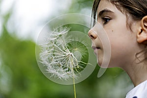 Girl outdoors blowing dandelion seeds.