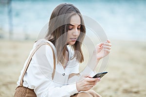 Girl outdoors texting on her mobile phone. Girl with phone. Portrait of a happy woman text sms message on her phone.