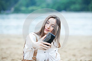 Girl outdoors texting on her mobile phone. Girl with phone. Portrait of a happy woman text sms message on her phone.