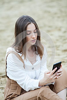 Girl outdoors texting on her mobile phone. Girl with phone. Portrait of a happy woman text sms message on her phone.