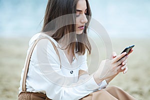 Girl outdoors texting on her mobile phone. Girl with phone. Portrait of a happy woman text sms message on her phone.