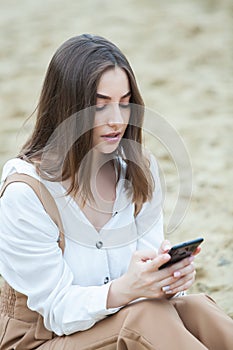 Girl outdoors texting on her mobile phone. Girl with phone. Portrait of a happy woman text sms message on her phone.