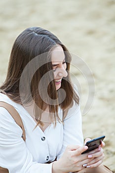 Girl outdoors texting on her mobile phone. Girl with phone. Portrait of a happy woman text sms message on her phone.