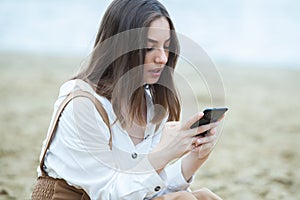 Girl outdoors texting on her mobile phone. Girl with phone. Portrait of a happy woman text sms message on her phone.