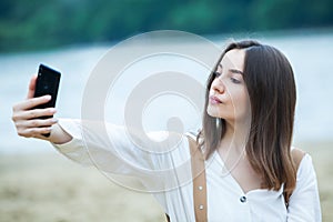 Girl outdoors texting on her mobile phone. Girl with phone. Portrait of a happy woman text sms message on her phone.