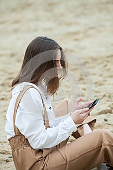 Girl outdoors texting on her mobile phone. Girl with phone. Portrait of a happy woman text sms message on her phone.