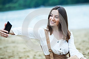 Girl outdoors texting on her mobile phone. Girl with phone. Portrait of a happy woman text sms message on her phone.