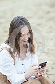 Girl outdoors texting on her mobile phone. Girl with phone. Portrait of a happy woman text sms message on her phone.