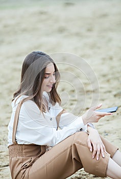 Girl outdoors texting on her mobile phone. Girl with phone. Portrait of a happy woman text sms message on her phone.