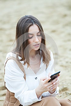 Girl outdoors texting on her mobile phone. Girl with phone. Portrait of a happy woman text sms message on her phone.