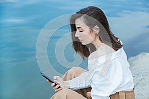 Girl outdoors texting on her mobile phone. Girl with phone. Portrait of a happy woman text sms message on her phone.