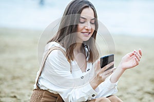 Girl outdoors texting on her mobile phone. Girl with phone. Portrait of a happy woman text sms message on her phone.