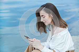 Girl outdoors texting on her mobile phone. Girl with phone. Portrait of a happy woman text sms message on her phone.