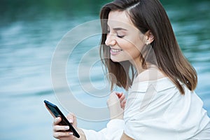 Girl outdoors texting on her mobile phone. Girl with phone. Portrait of a happy woman text sms message on her phone.