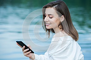 Girl outdoors texting on her mobile phone. Girl with phone. Portrait of a happy woman text sms message on her phone.