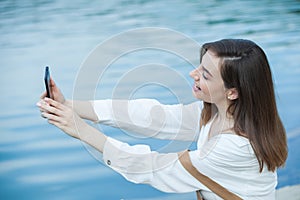 Girl outdoors texting on her mobile phone. Girl with phone. Portrait of a happy woman text sms message on her phone.