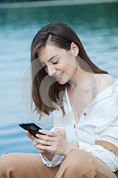 Girl outdoors texting on her mobile phone. Girl with phone. Portrait of a happy woman text sms message on her phone.