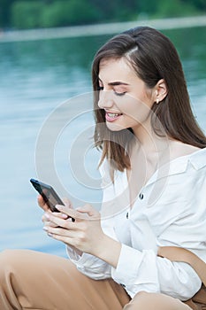 Girl outdoors texting on her mobile phone. Girl with phone. Portrait of a happy woman text sms message on her phone.