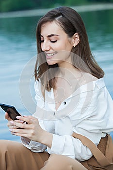 Girl outdoors texting on her mobile phone. Girl with phone. Portrait of a happy woman text sms message on her phone.
