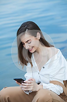 Girl outdoors texting on her mobile phone. Girl with phone. Portrait of a happy woman text sms message on her phone.