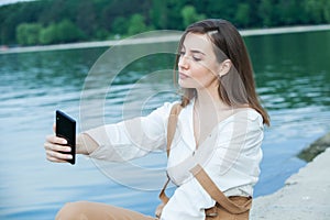 Girl outdoors texting on her mobile phone. Girl with phone. Portrait of a happy woman text sms message on her phone.